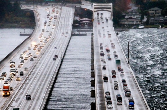 Eastbound traffic lanes, right, on Interstate 90 are dampened by wind-driven waves from the south as the floating bridge calms Lake Washington to the north, left, Tuesday, Nov. 17, 2015, in Seattle. Rain and high winds snarled the morning commute in the Puget Sound area and the Inland Northwest braced for severe weather that could include wind gusts to 70 mph. The National Weather Service says a Pacific storm system arriving Tuesday may include sustained winds of 45 mph that could topple trees and cause power outages. (AP Photo/Elaine Thompson)
